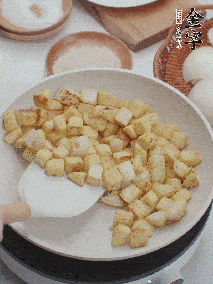 起鍋熱油，倒入饅頭丁，小火煎至蛋液凝固定型再翻面，饅頭丁部煎至金黃時(shí)盛起待用。