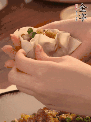 取一大勺餡料放進(jìn)餃子皮里，用大拇指按住頂部餡料，再用虎口掐出形狀。